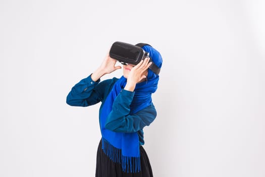 Asian muslim woman wearing hijab using VR headset glasses of virtual reality on white background