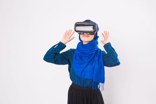 Asian muslim woman wearing hijab using VR headset glasses of virtual reality on white background