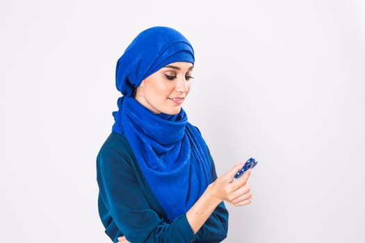 Young beautiful muslim girl holding and playing with fidget spinner. studio shot on white background