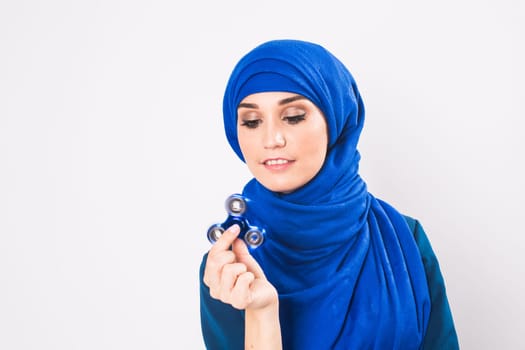 Young beautiful muslim girl holding and playing with fidget spinner. studio shot on white background