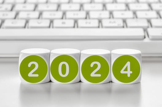 Letter dice in front of a keyboard - 2024