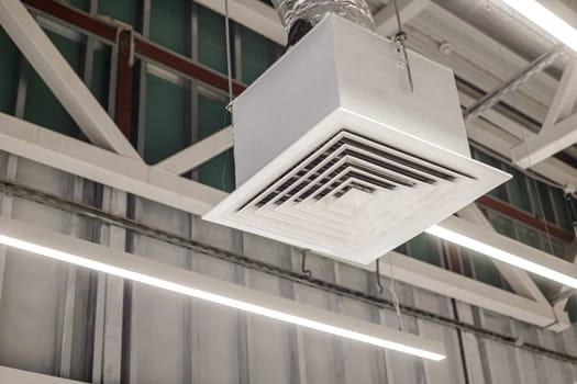 Square grille distributor with supply ventilation duct in a commercial building. Industrial office ventilation system