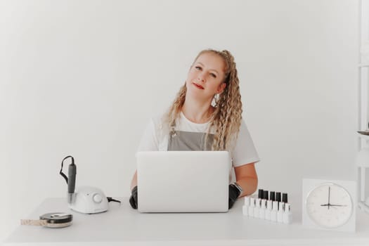 Woman Professional Manicurist at her Desk Works with a Laptop. Sign up for manicure services, freelancer work schedule