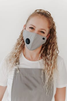 Close up portrait of Caucasian middle-aged woman in working uniform mask and apron looking at camera. White background
