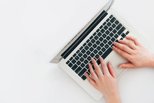 Woman hands using laptop computer from above on white table, copy space for text