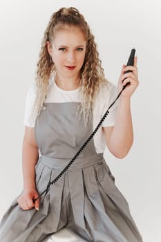 Woman nails artist in gray uniform holding manicure machine in her hand. White background
