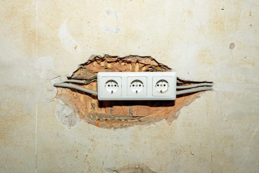 Electrical outlet in the wall of a house with broken electrical wires