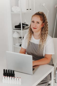 Woman Professional Manicurist at her Desk Works with a Laptop. Sign up for manicure Services, Freelancer Work Schedule