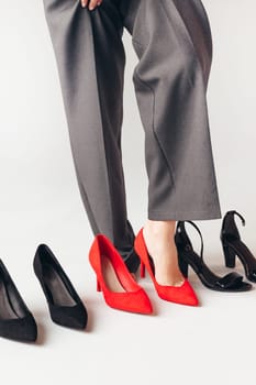 Woman choosing suitable shoes for evening or office. Trying on red ones.