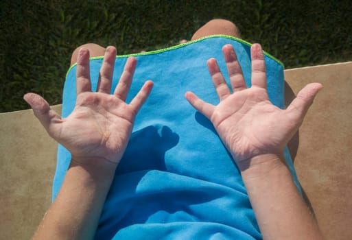 Child boy showing his wrinkled hands after swimming in the pool. Overhead view