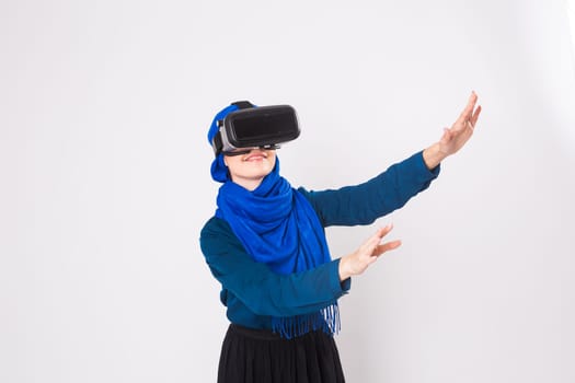 Asian muslim woman wearing hijab using VR headset glasses of virtual reality on white background