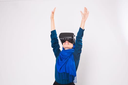 Asian muslim woman wearing hijab using VR headset glasses of virtual reality on white background