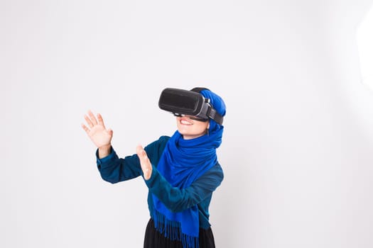 Asian muslim woman wearing hijab using VR headset glasses of virtual reality on white background