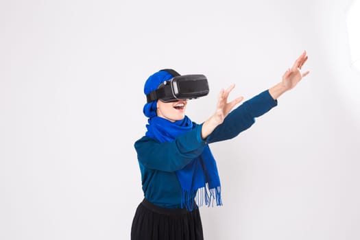 Asian muslim woman wearing hijab using VR headset glasses of virtual reality on white background