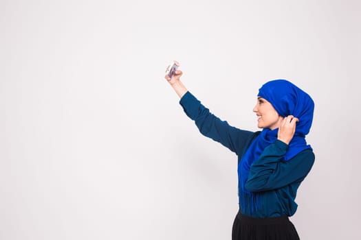 Portrait of beautiful muslim young woman wearing hijab take selfie using her mobile phone.
