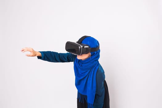 Asian muslim woman wearing hijab using VR headset glasses of virtual reality on white background