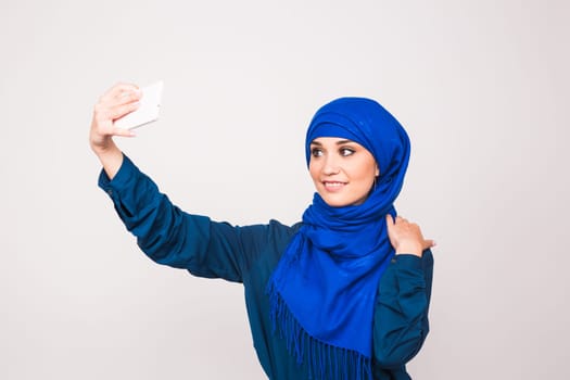 Portrait of beautiful muslim young woman wearing hijab take selfie using her mobile phone.