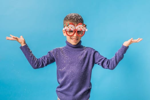 Child boy throws up on blue background. Christmas and New Year holidays concept. Generation alpha and gen alpha children. Copy space.