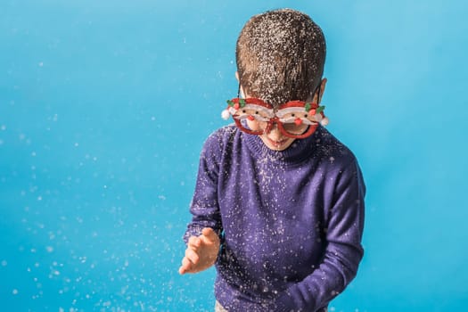 Child boy throws up on blue background. Christmas and New Year holidays concept. Generation alpha and gen alpha children. Copy space.