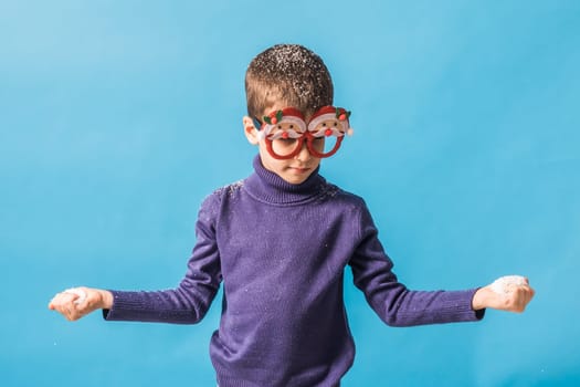 Child boy throws up on blue background. Christmas and New Year holidays concept. Generation alpha and gen alpha children. Copy space.