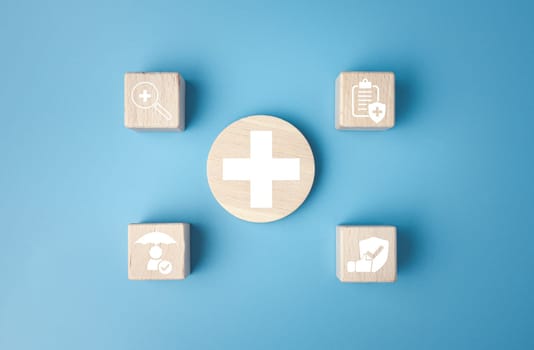 Concept of health insurance and medical. Wooden block with icons about health insurance and access to health care, health care planning on a blue background.
