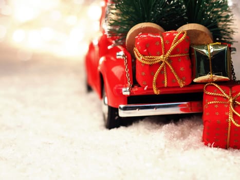 Red Christmas truck with Christmas trees and gift boxes in the snow, selective focus on the foreground, space for your text on the right side
