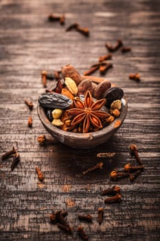 Christmas spices for baking cookies, Stollen or mulled wine in small bowl on wooden background.