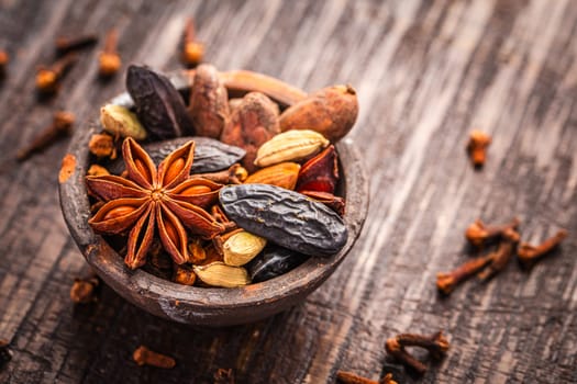 Christmas spices for baking cookies, Stollen or mulled wine in small bowl on wooden background.