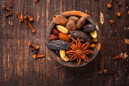 Christmas spices for baking cookies, Stollen or mulled wine in small bowl on wooden background.