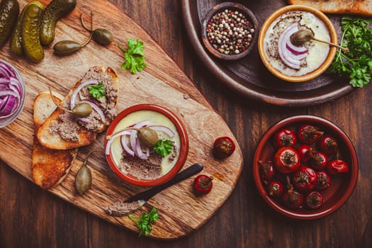 Fresh homemade chicken liver pate in ceramic bowls and appetizers on rustic background