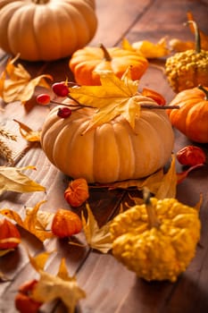 Autumn still life with pumpkins and leaves on wooden background. Thanksgiving home decoration.