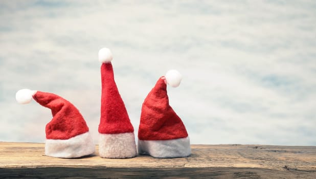 Three hat of Santa on a wooden board with space for text