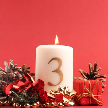 Third Advent candle burns, white candle with the number three on a red background, Christmas decoration, space for text