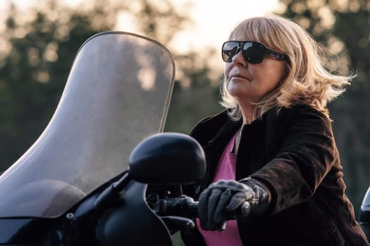 Confident pretty mature blonde in leather gloves driving her bike on autumn day. Hobby motorcycle tourism. Healthy lifestyle. Emotional relief. Excellent physical shape. Tourism and travel.