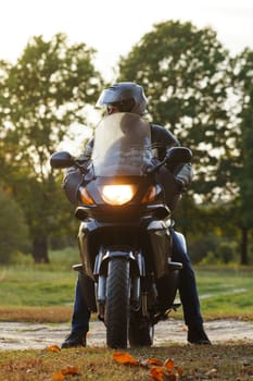 Vertical image. Unrecognizable person on motorcycle in nature in autumn during parking. Motorcycle tourism. Healthy . Sport and strength of character. Excellent physical shape. Motorcycle equipment.