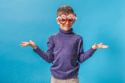 Child boy throws up on blue background. Christmas and New Year holidays concept. Generation alpha and gen alpha children. Copy space.