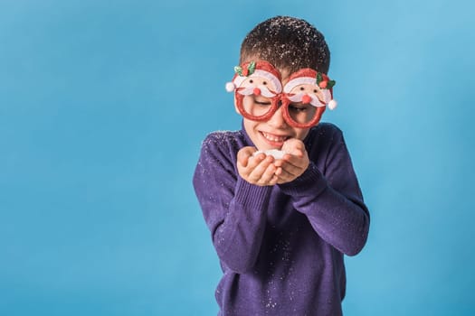 Child boy throws up on blue background. Christmas and New Year holidays concept. Generation alpha and gen alpha children. Copy space.