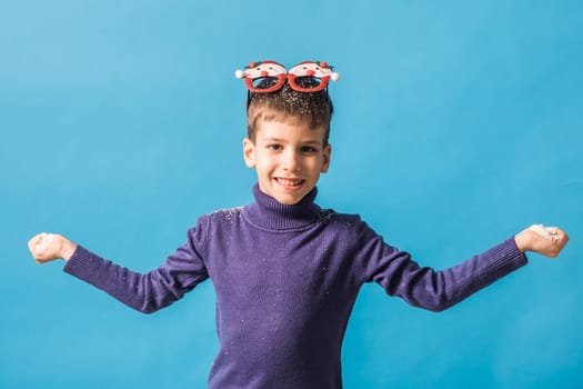 Child boy throws up on blue background. Christmas and New Year holidays concept. Generation alpha and gen alpha children. Copy space.