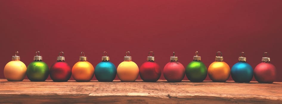 Old used vintage Christmas balls on a rustic wooden table with a red background and space for text, using as header or backdrop