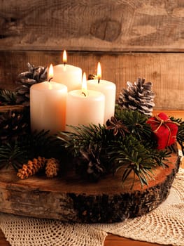 Fourth Advent, one candle burning on a rustic wooden table with Christmas decoration