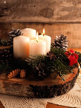 Second Advent, one candle burning on a rustic wooden table with Christmas decoration