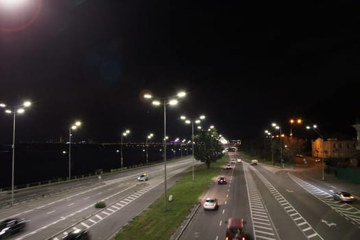 Evening transport. Cars on the night highway. Multi-lane road in Kyiv at night. Illuminated street of evening city. Cars going along night city