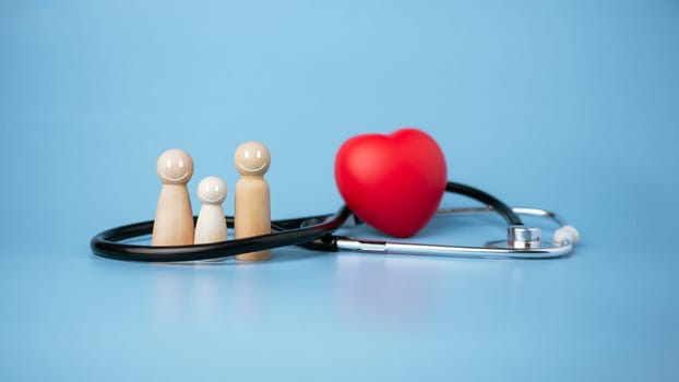 Concept of health insurance and medical welfare, wooden doll and red heart with stethoscope on blue background, health insurance and access to healthcare.