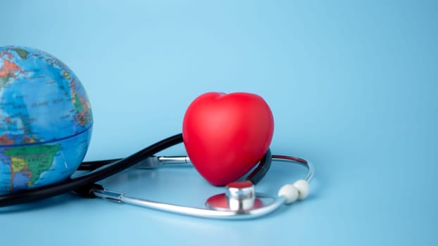 Concept of health insurance and medical welfare, model globe and red heart with stethoscope on blue background, health insurance and access to healthcare.
