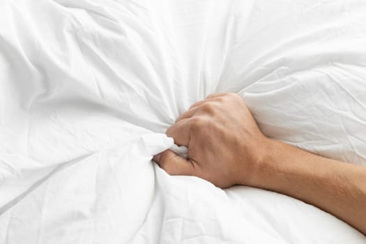 Man's hand squeezing a blanket, vintage white, soft focus. High quality photo