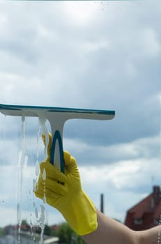 Window cleaning with a scraper and window cleaner. Cleaning in a house or apartment. Removing dirt from windows and windows. High quality photo
