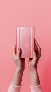female hands holding a closed book on a pink background. top view, copy space.Generative AI