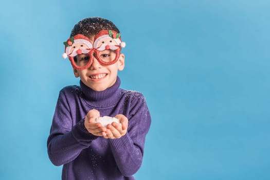Child boy throws up on blue background. Christmas and New Year holidays concept. Generation alpha and gen alpha children. Copy space.