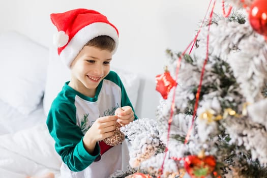 Close up of caucasian child hands putting ornaments on Christmas tree style in gold and white color