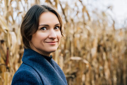 Portrait of attractive young woman in autumn coat in cornfield.